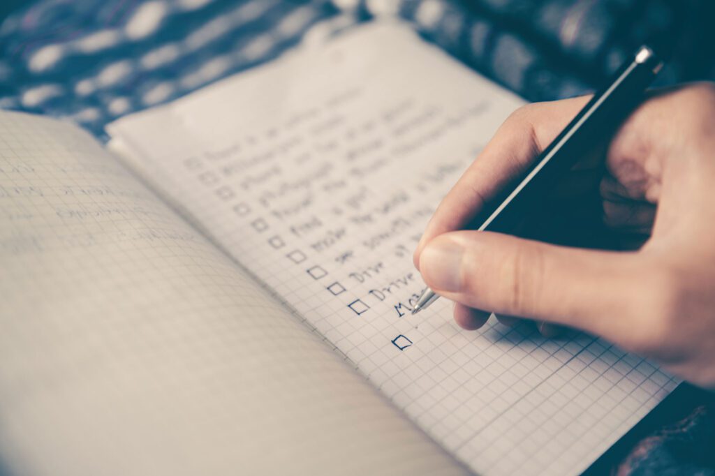 A person writing on a notebook with a pen.